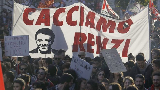 People march behind a banner portraying Italian premier Matteo Renzi and reading 