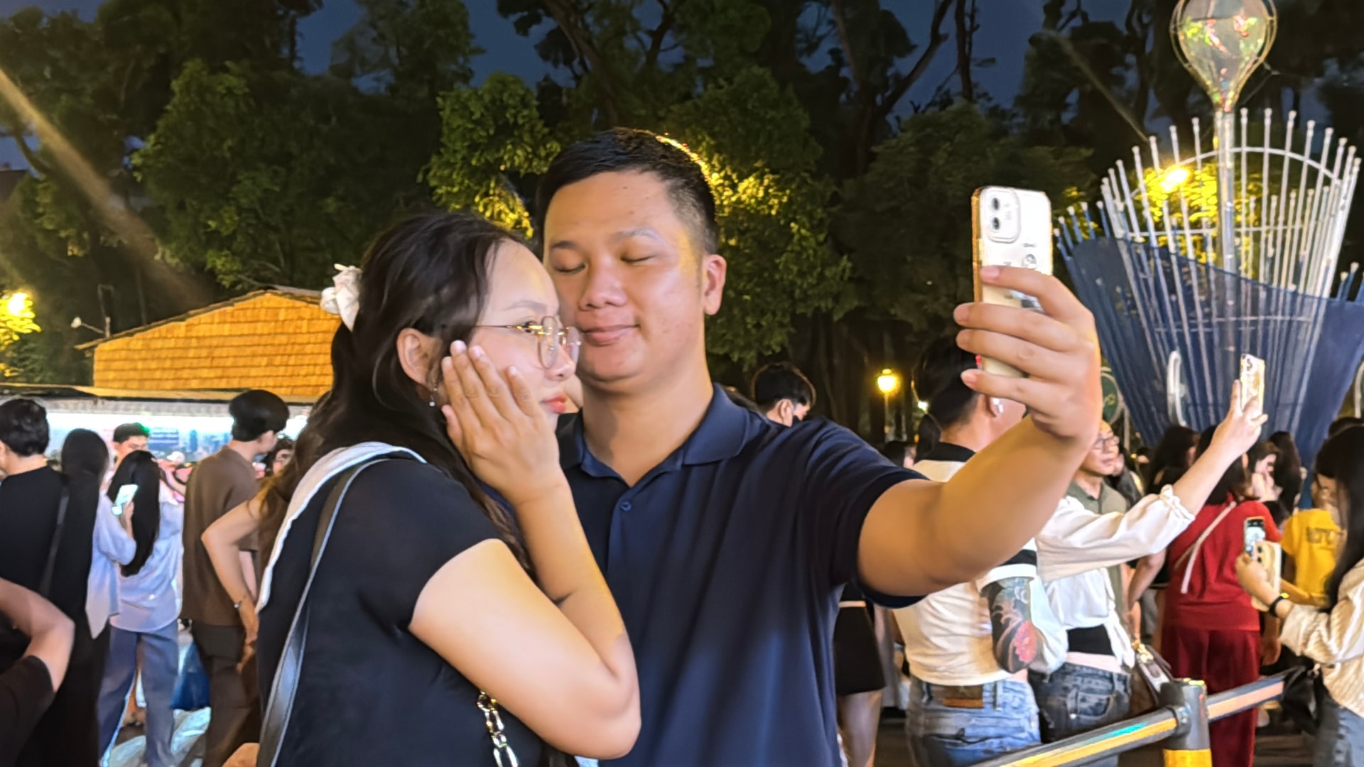 Một cặp đôi trẻ tranh thủ lưu giữ khoảnh khắc đầu năm bằng chiếc điện thoại trên tay, giữa dòng người đông đúc tại khu vực trung tâm thành phố - Ảnh: Tiểu Vũ