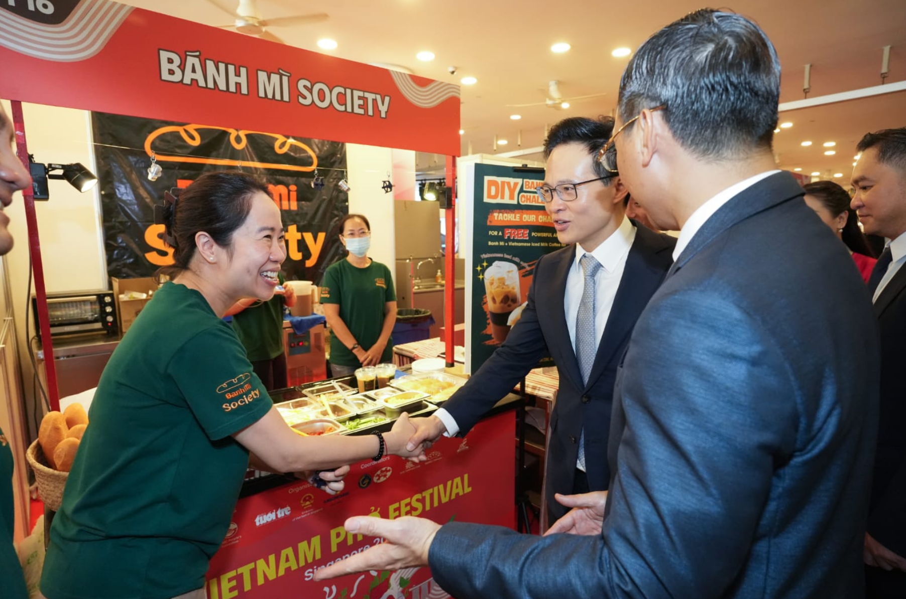 Ông Trần Phước Anh, Đại sứ Việt Nam tại Singapore và ông Desmond Choo, Quốc vụ khanh, Bộ Quốc phòng Singapore tại gian hàng Bánh mì Society của chị Hà Lâm Tú Quỳnh hồi tháng 10/2025. Ảnh: NVCC