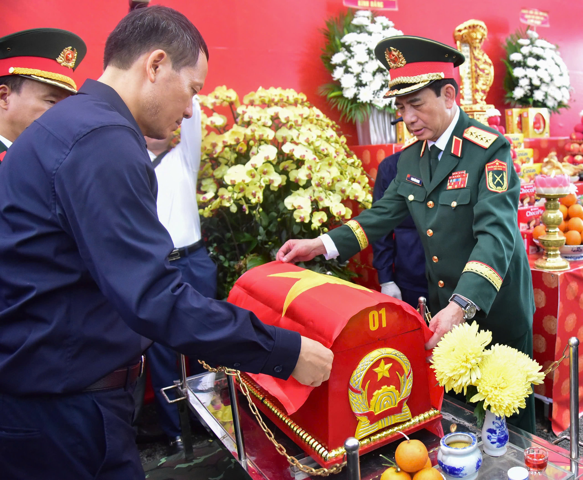Đại tướng Phan Văn Giang cùng Bí thư Thành ủy Đồng Nai Vũ Hồng Văn phủ cờ Tổ quốc lên hài cốt liệt sĩ được tìm thấy tại xã Minh Đức. Ảnh: Đức Nhân.