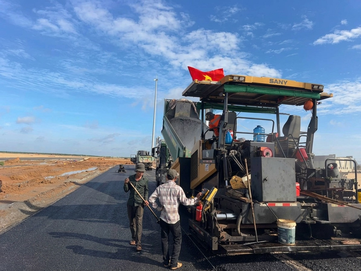 Công nhân và máy móc chuyên dụng đang tiến hành trải thảm nhựa asphalt cho một dự án sân bay Long Thành.