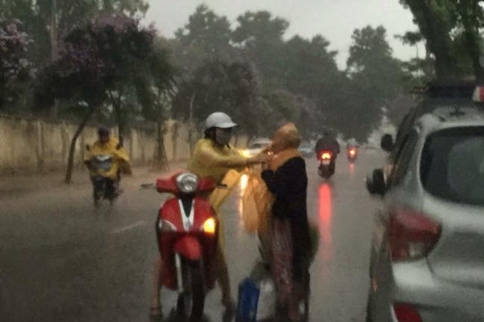 Cô gái đi xe máy mặc áo mưa cho cụ bà bán rau xa lạ giữa đường Hà Nội