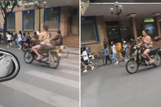 Cô gái vừa lái xe máy vừa đọc sách trên phố Hà Nội